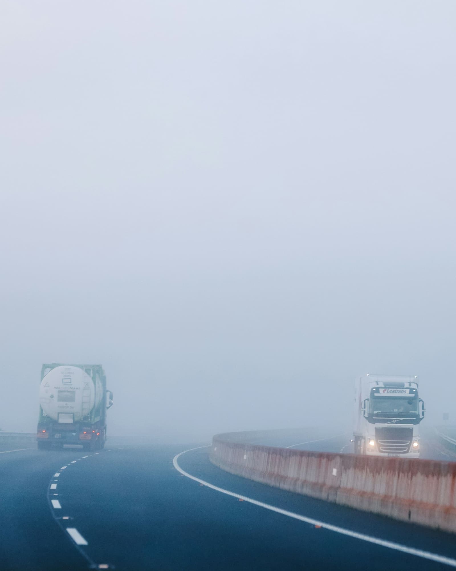 Articulated lorry approaching on a foggy motorway with a tanker ahead